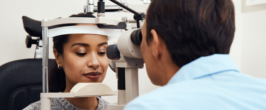 eye doctor performing an eye exam on a female patient in an eye doctor’s office